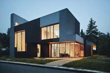 A modern two-story house at dusk with exterior lights on