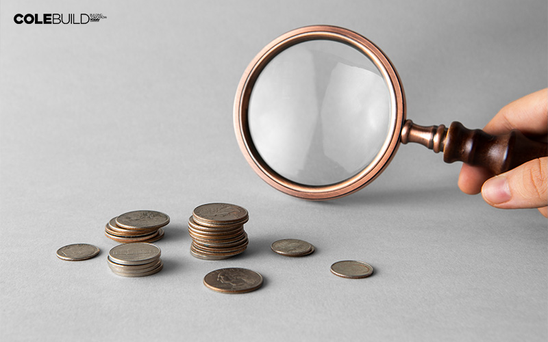 magnifying glass beside a pile of coins