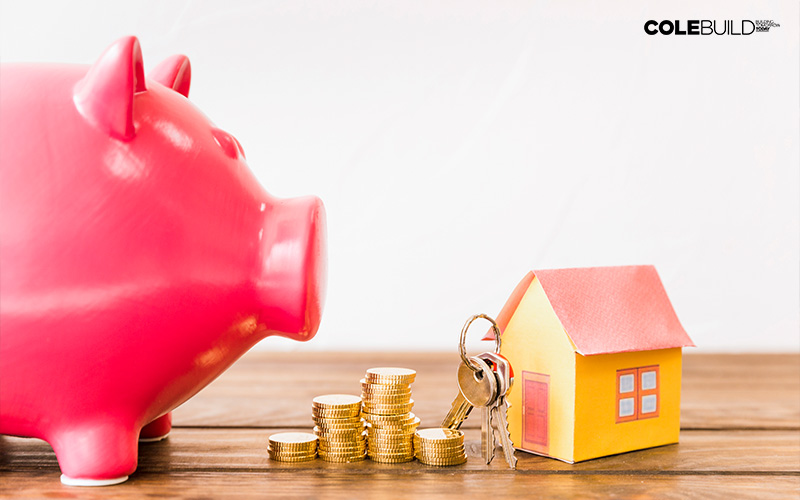 piggy bank and savings beside keys and a tiny house model